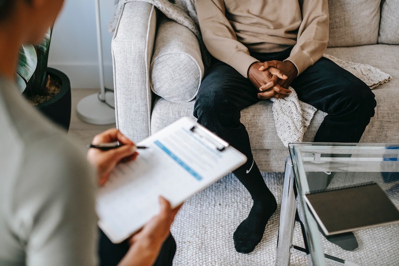 A therapist and a client meeting. They are sitting across from each other in a brightly lit room. One male and one female. The female therapist has a clipboard and pen in her hands. She's completing a form with the male client. Contact Choosing You Counselling & Psychotherapy to set up your first session.