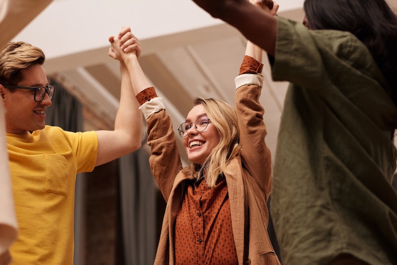 A group of individuals are all holding hands in a circle, with their arms raised. They are smiling and happy. Contact trauma informed, EMDR and Somatic Experiencing trained therapists today. Mental health support available online across Ontario.