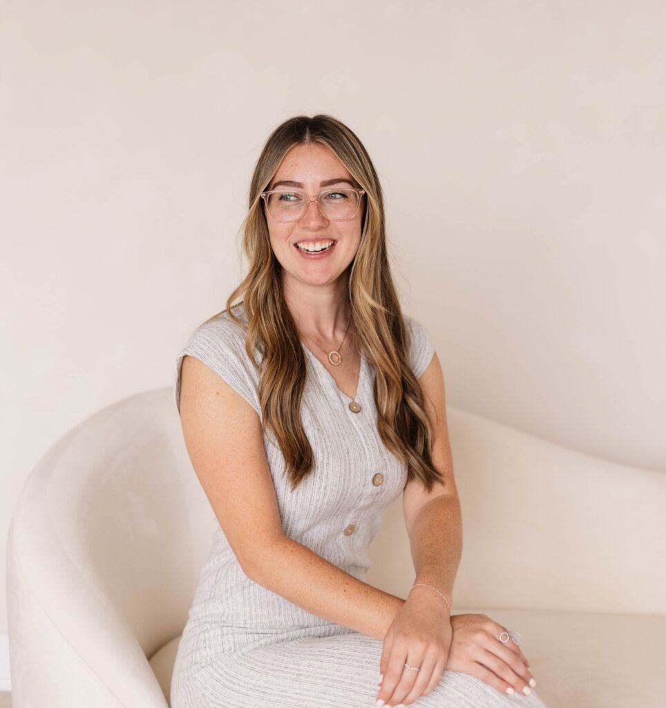 Kendra Grant is featured in the photo sitting down on a cream couch. Her hand are crossed, she is looking away from the camera smiling. Contact trauma informed, EMDR and Somatic Experiencing trained therapists today. Mental health support available online across Ontario. Supporting Healthcare workers.
